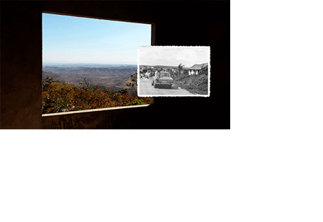 Foto horizontal do requadro de uma janela, visto de dentro de uma construção. A parede é de cimento e está bem escura, quase preta. A janela está em perspectiva, da esquerda para a direita. Lá fora vê-se uma bonita paisagem, com o cerrado em tons de marrom e verde, e morros que vão ficando azuis até sumirem no horizonte azul claro. A janela ocupa dois terços da foto. No terço restante, à direita, está colada uma foto menor, antiga, em preto e branco, mostrando uma estrada de terra em perspectiva, um carro (corcel anos 70) e uma criança sentada no capô traseiro. Vê-se uma casinha ao lado e uma pequena cidade ao longe. A foto menor está ligeiramente sobre a maior, e as linhas do horizonte das duas coincidem.