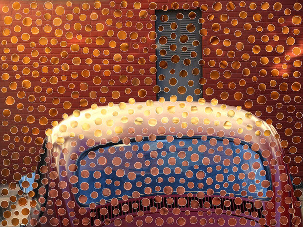 Foto horizontal de parte de um fusca vermelho antigo, visto de trás. Ele aparece só do meio para cima, incluindo o parabrisa, e ocupa a metade de baixoda imagem. A metade de cima mostra uma parede vermelho escuro e uma estreita porta cinza chumbo. Sobre toda a superfície foram coladas bolinhas recortadas de outras fotos, em tons de laranja, vermelho, rosa, amarelo, vinho e marrom. Elas estão bem próximas umas das outras e fazem uma espécie de degradê, acompanhando os tons da foto. Seus formatos são irregulares e estão contornados por uma linha clara, também irregular. Essas bolinhas fazem referência a obras de Athos Bulcão.