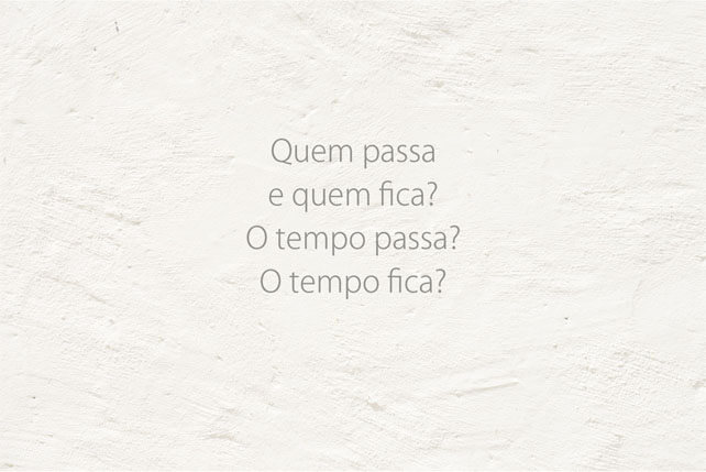 Imagem horizontal de uma parede branca com a quarta frase, em quatro linhas: Quem passa / e quem fica? / O tempo passa? / O tempo fica?